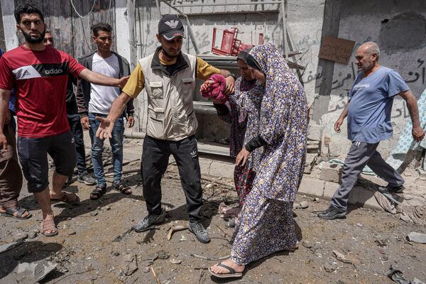 Рањену Палестинку воде до кола хитне помоћи након израелског напада на камп Ал-Буреиј у централном Појасу Газе. - Sputnik Србија