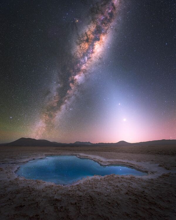 „Plava laguna pod zvezdama“ Jurija Beleckog slikana je u pustinji Atakama, u Čileu. Kako je sam autor rekao, u tom trenutku galaksija je već sijala visoko na nebu, sa zodijačkom svetlošću koja ju je lepo dopunjavala na desnoj strani. - Sputnik Srbija