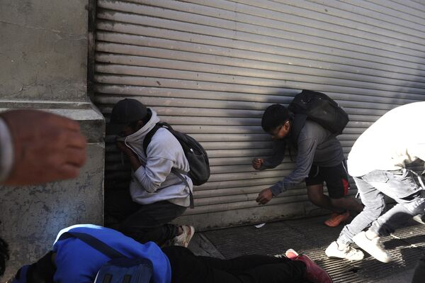 Narod skriva lice od suzavca koji je ispalila vojna policija ispred palate Kemado na trgu Muriljo u La Pazu - Sputnik Srbija