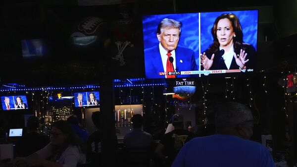 People watch TV screens showing a debate between Democratic presidential nominee Vice President Kamala Harris, right, and Republican presidential nominee former President Donald Trump, at Sports Grill Kendall, where the Miami-Dade Democratic Hispanic Caucus had organized a watch party, Tuesday, Sept. 10, 2024, in Miami.  - Sputnik Србија