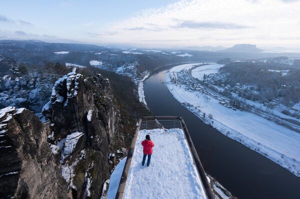 Turista na vidikovcu na steni Bastei u snegom prekrivenom Nacionalnom parku Saksonska Švajcarska. - Sputnik Srbija