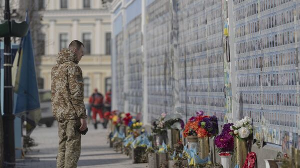 Ukrajinski vojnik pored memorijalnog zida sa fotografijama poginulih ukrajinskih vojnika u Kijevu - Sputnik Srbija