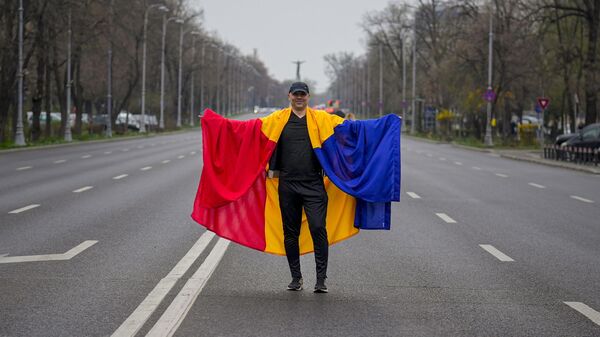 Čovek ogrnut rumunskom zastavom pozira na praznom bulevaru, tokom mitinga koji je organizovala Alijansa za Uniju Rumuna (AUR), u Bukureštu, Rumunija - Sputnik Srbija
