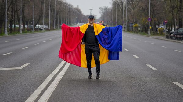 Човек огрнут румунском заставом позира на празном булевару, током митинга који је организовала Алијанса за Унију Румуна (АУР), у Букурешту, Румунија - Sputnik Србија