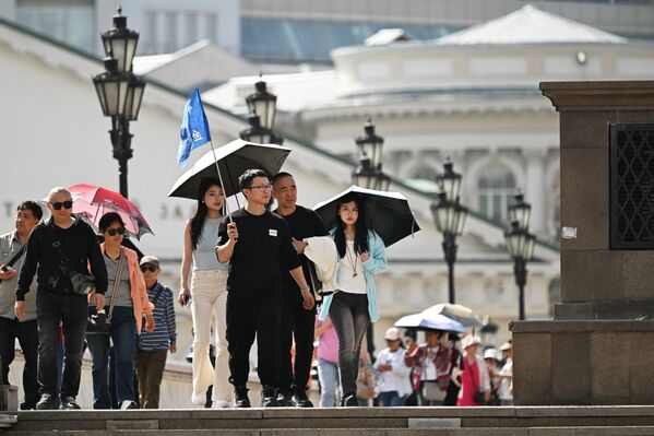 Kineski turisti se kišobranima štite od sunčevih zraka. - Sputnik Srbija