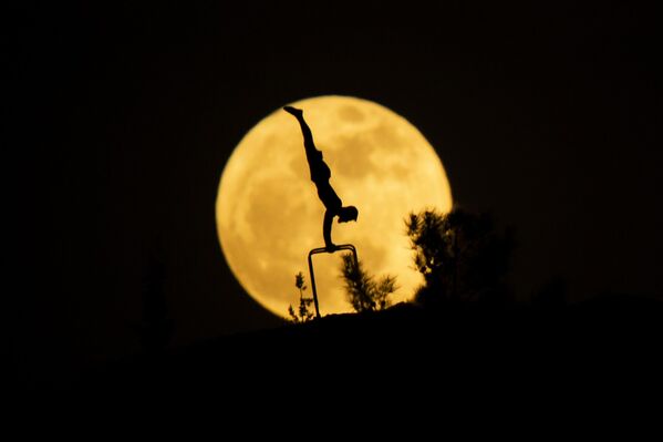 Пун месец се у позадини силуете човека који вежба гимнастику у Ербилу, Ирак Пун месец се у позадини силуете човека који вежба гимнастику у Ербилу, Ирак - Sputnik Србија