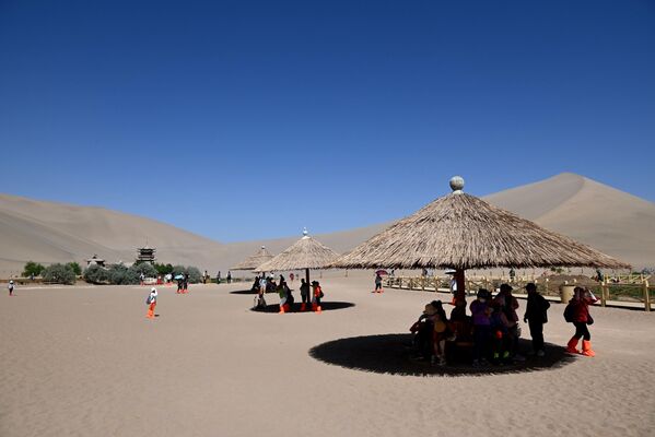 На фотографији су приказани туристи у посети планини Мингша и живописном месту Кресент Спринг у Дунхуангу, провинција Гансу у Кини. - Sputnik Србија