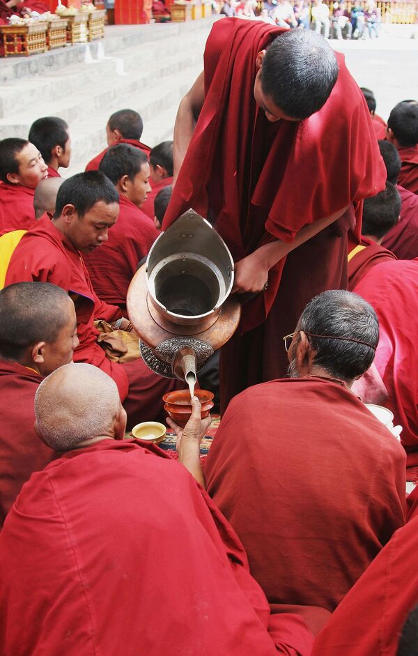 Ламе пију чај од путера док гледају представу верског Плеса вила у манастиру Ташилунпо 7. октобра 2005. у Шигадзеу, Тибетска аутономна област, Кина. - Sputnik Србија