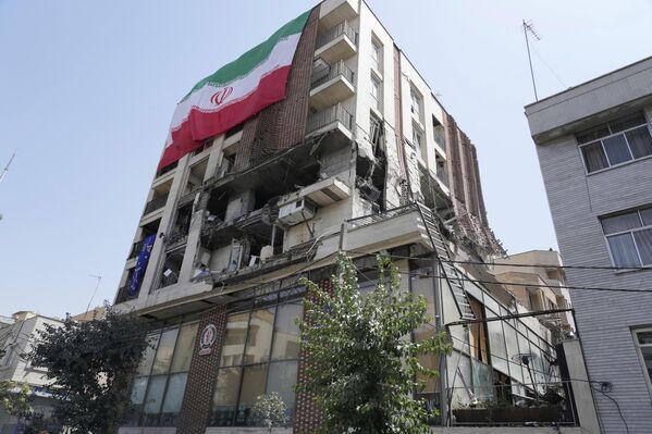 Иранска застава виси на згради која је погођена у израелском  нападу прошле недеље у Техерану. - Sputnik Србија