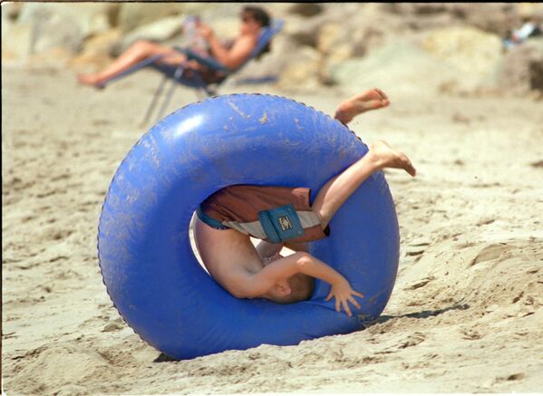 Џош Дејл (11) из Охаја, котрља се низ песак у гуменом прстену ка океану на плажи Ема Вуд у Вентури. - Sputnik Србија