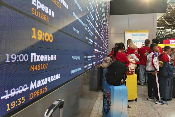 Путници стоје у реду за пријаву на први лет који повезује Москву и Пјонгјанг, док табла са информацијама о летовима приказује време поласка. - Sputnik Србија