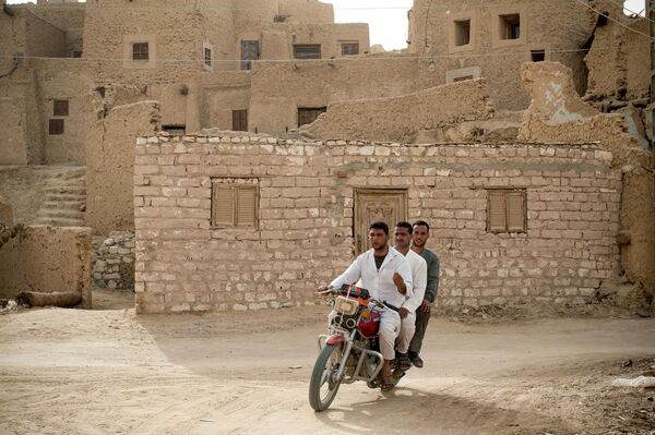 Три Египћана возе мотоцикл у рушевинама тврђаве Шали. Оаза Сива, урбана оаза у Египту која се налази између депресије Катара и Великог пешчаног мора у Западној пустињи Северне Африке. - Sputnik Србија
