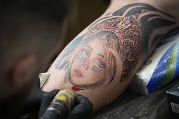 Мушкарац тетовира девојку која носи кокошник током фестивала тетоважа у Москви, - Sputnik Србија