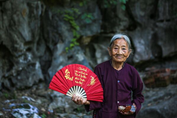 Старија жена позира држећи лепезу  - Sputnik Србија