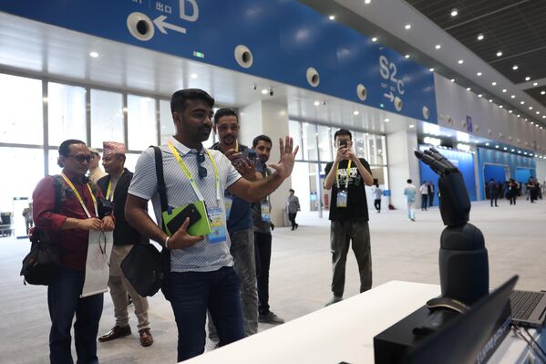 Новинар интерагује са роботском руком у Медијском центру за самит ШОС-а. Медијски центар садржи више различитих области, укључујући сервисну зону, јавни радни простор за медије, наменске канцеларије за штампу, салу за саопштења за штампу и интерактивни технолошки и изложбени културни простор. - Sputnik Србија