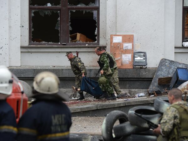 Arhivska fotografija od 2.6.2014. Pripadnici samoodbrane odnose telo čoveka poginulog u vazdušnom napadu ukrajinskog vazduhoplovstva na zgradu regionalne administracije u Lugansku. - Sputnik Srbija
