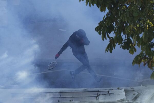 Демонстрант бежи од сузавца који је испалила француска полиција. - Sputnik Србија