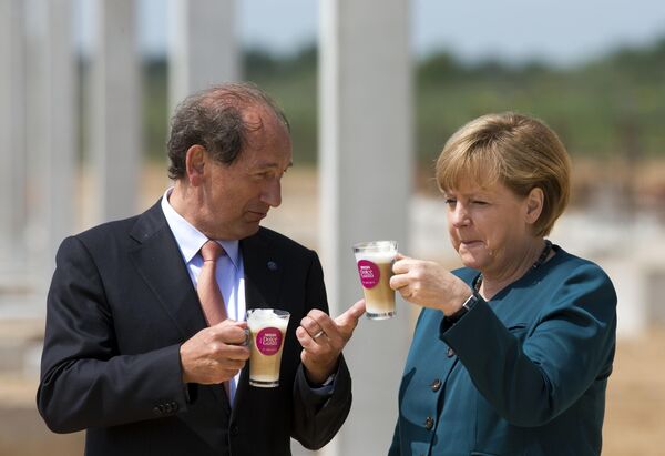 Немачка канцеларка Ангела Меркел и извршни директор компаније Nestlé Пол Булке пију кафу током церемоније постављања камена темељца за нову фабрику капсула кафе Nestlé у Шверину, Немачка, 31. маја 2013. - Sputnik Србија