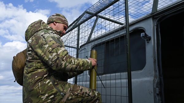 Voennoslužaщiй podgotavlivaet avtomobilь s ustanovlennыm zaщitnыm mangalom ot atak BPLA k ispыtaniяm - Sputnik Srbija