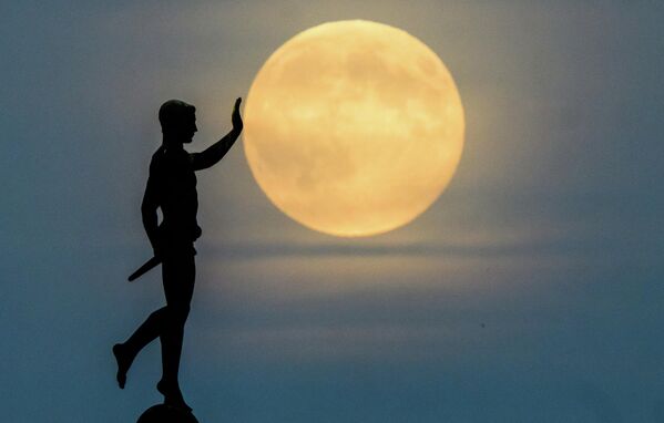 Mesec izlazi na horizontu iza statue ,,Nositelj baklje&#x27;&#x27; na severnoj obali jezera Mašze. - Sputnik Srbija