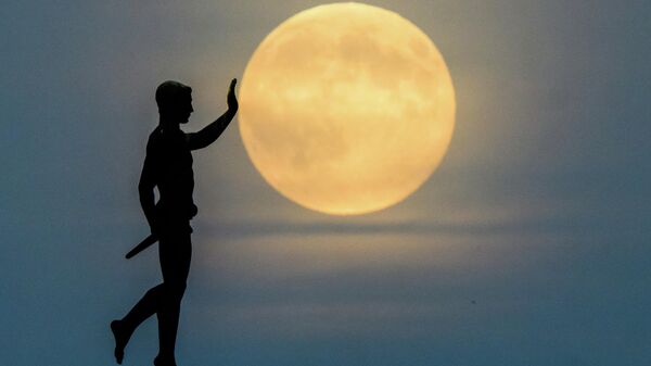 Luna voshodit na gorizonte za statueй Fakelonosec (1937) na severnom beregu ozera Maš, Germaniя - Sputnik Srbija