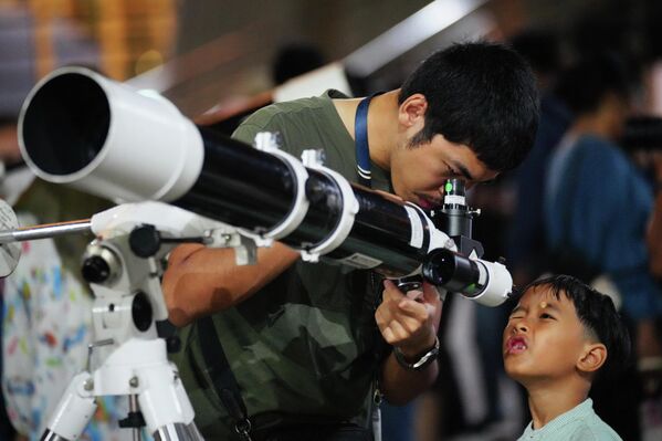 Čovek uz pomoć teleskopa posmatra izlazak meseca u Džakarti, Indonezija. - Sputnik Srbija