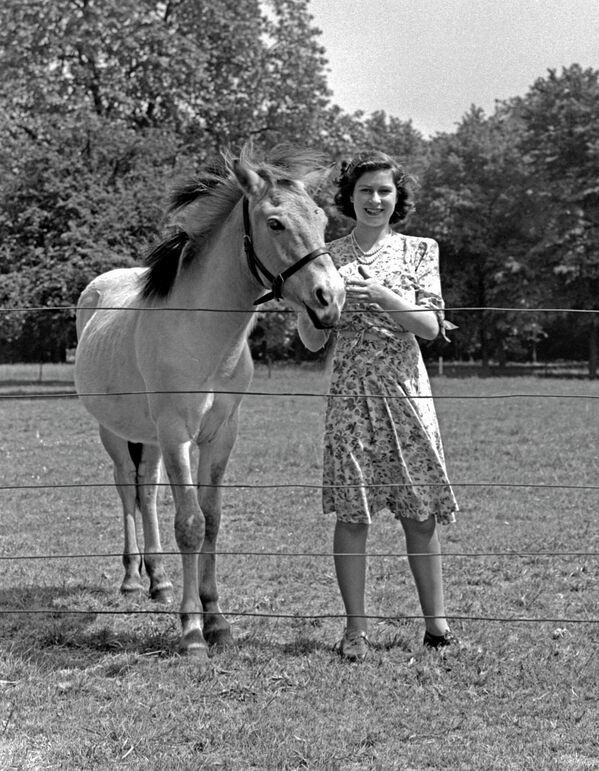 Принцеза Елизабета (краљица Елизабета II) фотографисана поред коња у башти замка Виндзор, Беркшир, Велика Британија, 1944. - Sputnik Србија