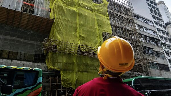 Rabočiй-stroitelь stoit vozle remontiruemogo zdaniя v raйone Mong Kok posle požara, Gonkong - Sputnik Srbija