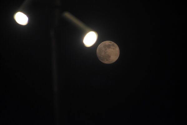 Poslednji supermesec, poznat i kao Hladni mesec, izlazi iza uličnih svetala u Srinagaru u Indiji. - Sputnik Srbija