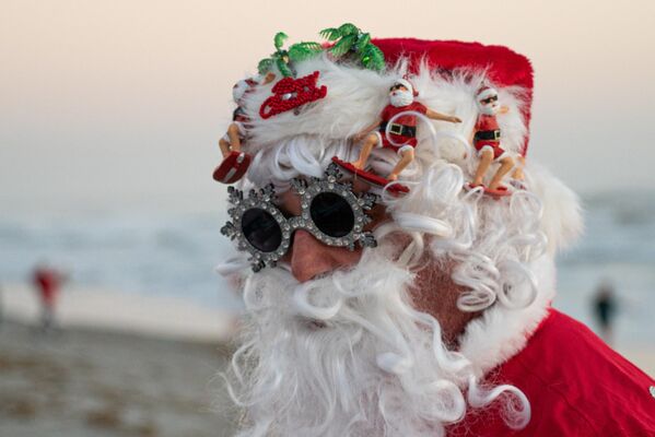 Surfer obučen kao Deda Mraz na tradicionalnoj manifestaciji „Surfovanje Deda Mraza“, koji se održava u okviru proslave Badnje večeri na Floridi - Sputnik Srbija