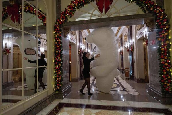 Član hotelskog osoblja pomaže maskoti polarnog medveda nakon što je zabavio goste uoči Božića u Pekingu. - Sputnik Srbija