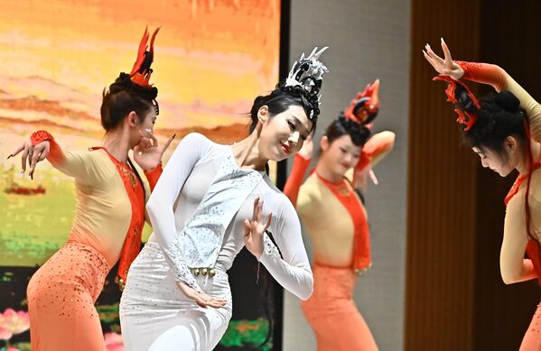 Грациозне плесачице у традиционалним костимима и украсима за главу који подсећају на феникса или змаја. Феникс се слично змају у Кини повезује са срећом и божанском моћи, док наранџаста боја симболизује ватру - Sputnik Србија