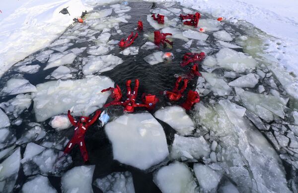 Ентузијасти потапају у реку Москва током сеансе плутања по леду, зимске активности у којој учесници плутају у хладној води носећи термална сува одела, у Москви. - Sputnik Србија