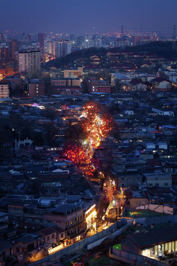 Градска расвета осветљава улицу оивичену црвеним фењерима уочи празника у области Модекоу, на периферији Пекинга. - Sputnik Србија