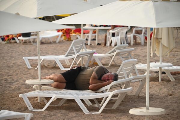Човек спава на лежаљци на плажи у Геленџику. - Sputnik Србија