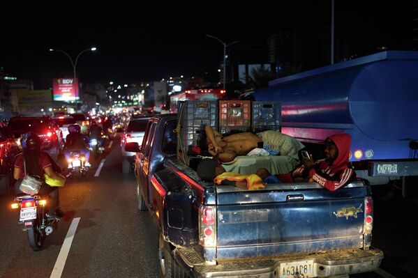 Човек спава на задњем седишту пикапа заглављеног у саобраћајној гужви у Каракасу, Венецуела. - Sputnik Србија