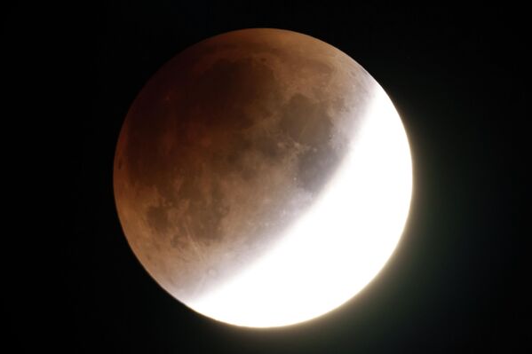 Pun Mesec u obliku crva svetli narandžasto dok se približava potpunosti tokom pomračenja Meseca u ranim jutarnjim satima u godine, blizu Moskve, Ajdaho. - Sputnik Srbija