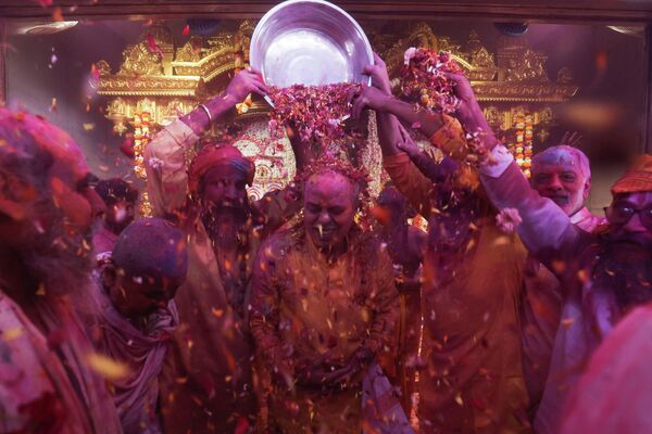 Хиндуистички свети људи посипају верника латицама цвећа помешаним са прахом боје. - Sputnik Србија