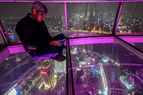 Мушкарац се фотографише на видиковцу једног од небодера у Шангају. - Sputnik Србија