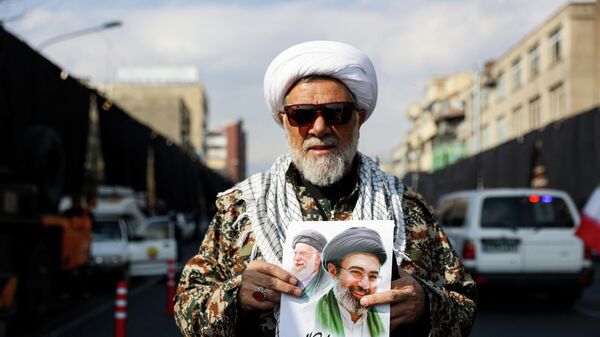 Мужчина держит плакат с изображением нового верховного лидера Ирана Моджтабы Хаменеи и покойного верховного лидера Ирана аятоллы Али Хаменеи, Иран - Sputnik Србија