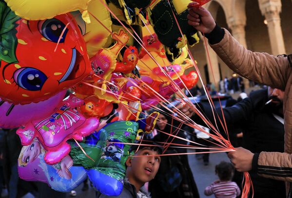 Дечак посматра балоне које продаје улични продавац, док се верници окупљају испред џамије Мохамед ел Амин у Бејруту. - Sputnik Србија