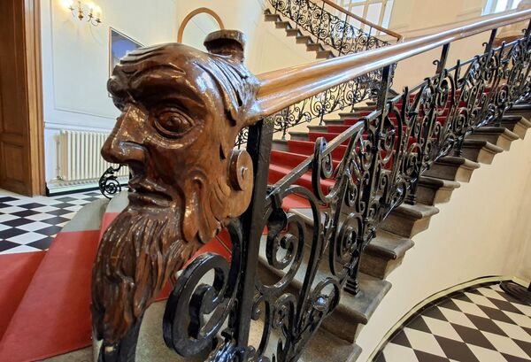 Ограду израђену од кованог гвожђа, обликованог у сложене спиралне мотиве и узорке лишћа, краси завршни детаљ дрвеног рукохвата, обликован као мушка глава са брадом. - Sputnik Србија