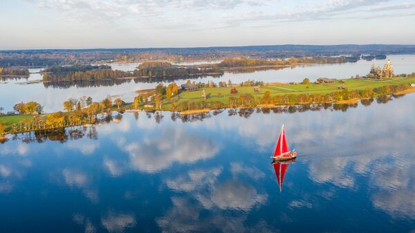 Експедициона јахта „Петар Први“ поред острва Кижи. У другом плану — Преображењска црква из XVIII века, црква Покрова Пресвете Богородице и звоник, који чине део архитектонског ансамбла Државног историјско-архитектонског музеја-резервата „Кижи“ у Карелији. - Sputnik Србија
