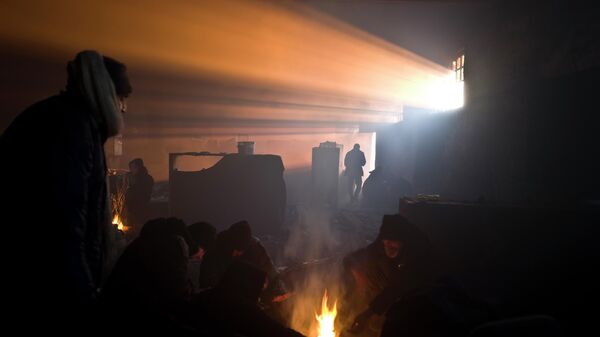 Људи се греју око ватре у напуштеном складишту - Sputnik Србија