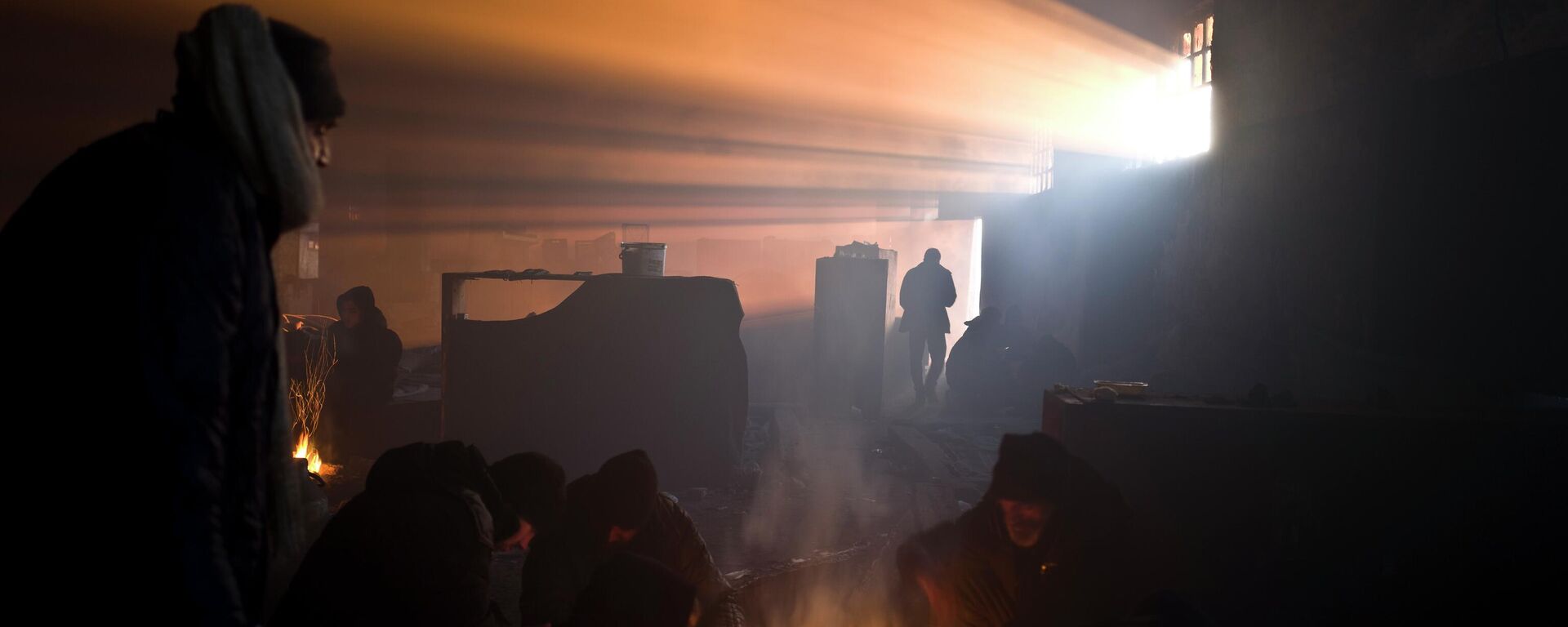 Људи се греју око ватре у напуштеном складишту - Sputnik Србија, 1920, 22.04.2026