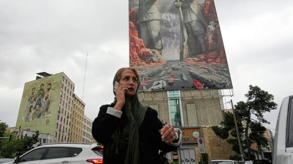 Женщина c мобильным телефоном на фоне плаката с изображением иранского военачальника Раиса-Али Дельвари и командующего ВМС КСИР Алирезы Тангсири в Тегеране, Иран - Sputnik Србија