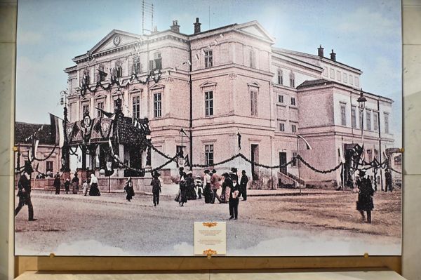 Једна од фотографија које посетиоцу "приповедају" догађаје који су се збили пре више од једног века, је и фотографија настала 12. јуна 1903. године којом је овековечена свечано декорисана зграда Народног позоришта поводом дочека краља Петра Првог Карађорђевића  - Sputnik Србија