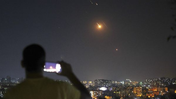 A man takes a cellphone photo as missiles fired from Iran toward Israel fly over Syrian territory in Damascus - Sputnik Srbija