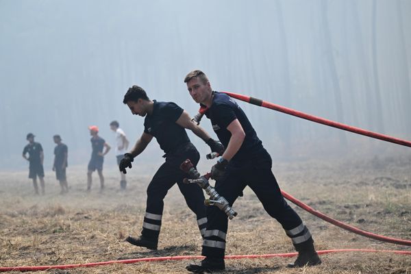 Vatrogasci razvlače creva dok se bore sa požarima u blizini La Berl de Kasija, tokom šumskih požara na jugozapadu Francuske. - Sputnik Srbija