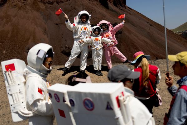 Grupa ljudi obučenih u kostime astronauta pozira za fotografije kod vulkana broj 6 u vulkanskom geoparku Ulanhada u Ulankabu, u Autonomnoj oblasti Unutrašnja Mongolija, Kina, 26. jula 2026. godine. U severnom delu Kine, u Unutrašnjoj Mongoliji, crne vulkanske stene pretvorile su ovaj prostor u svojevrsni simulator Marsa. Posetioci iznajmljuju bele ili roze kostime svemirskih odela i poziraju u pustom pejzažu, dok prodavci hrane nude sladoled u obliku astronauta sa ukusom jagode. - Sputnik Srbija